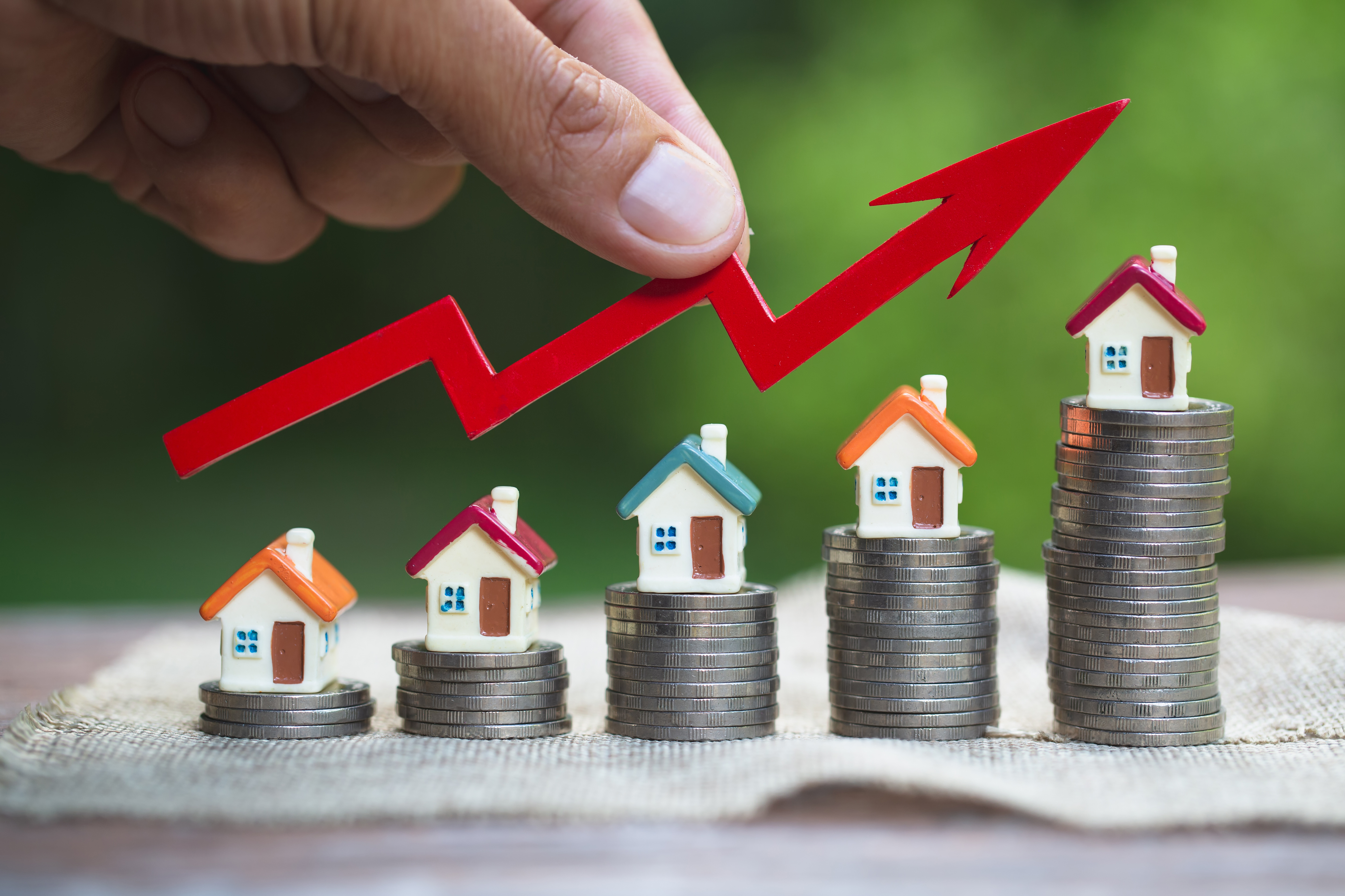 model houses on stacks of coins with an upward-trending arrow