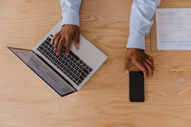 person reaching for their laptop and cellphone