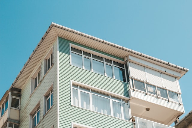 exterior of a green and white apartment building against a blue sky