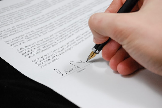 A hand signing a lease with a fountain pen