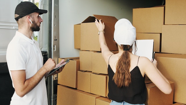 two people packing boxes into a moving van